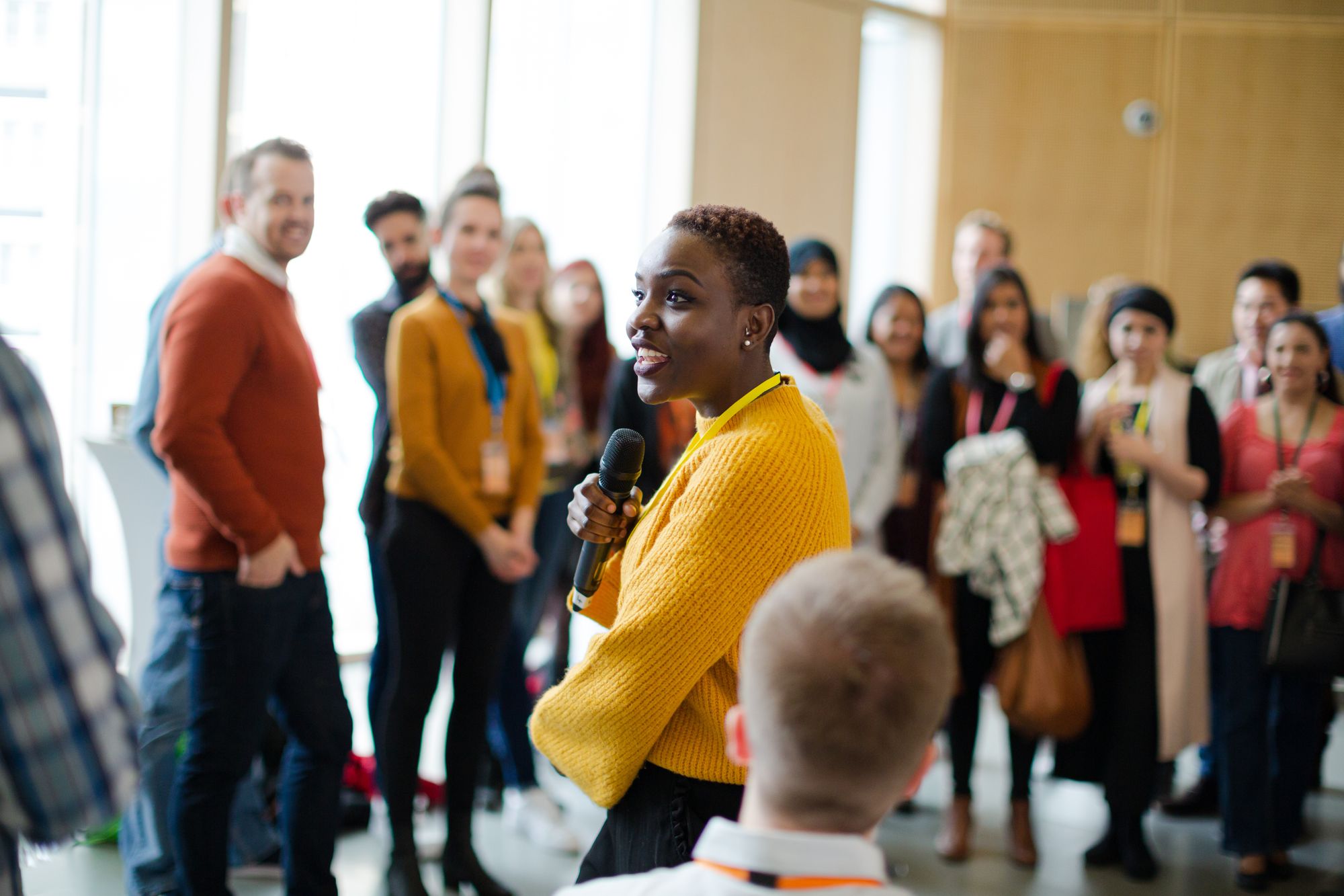 A presenter with a microphone speaking to a diverse group